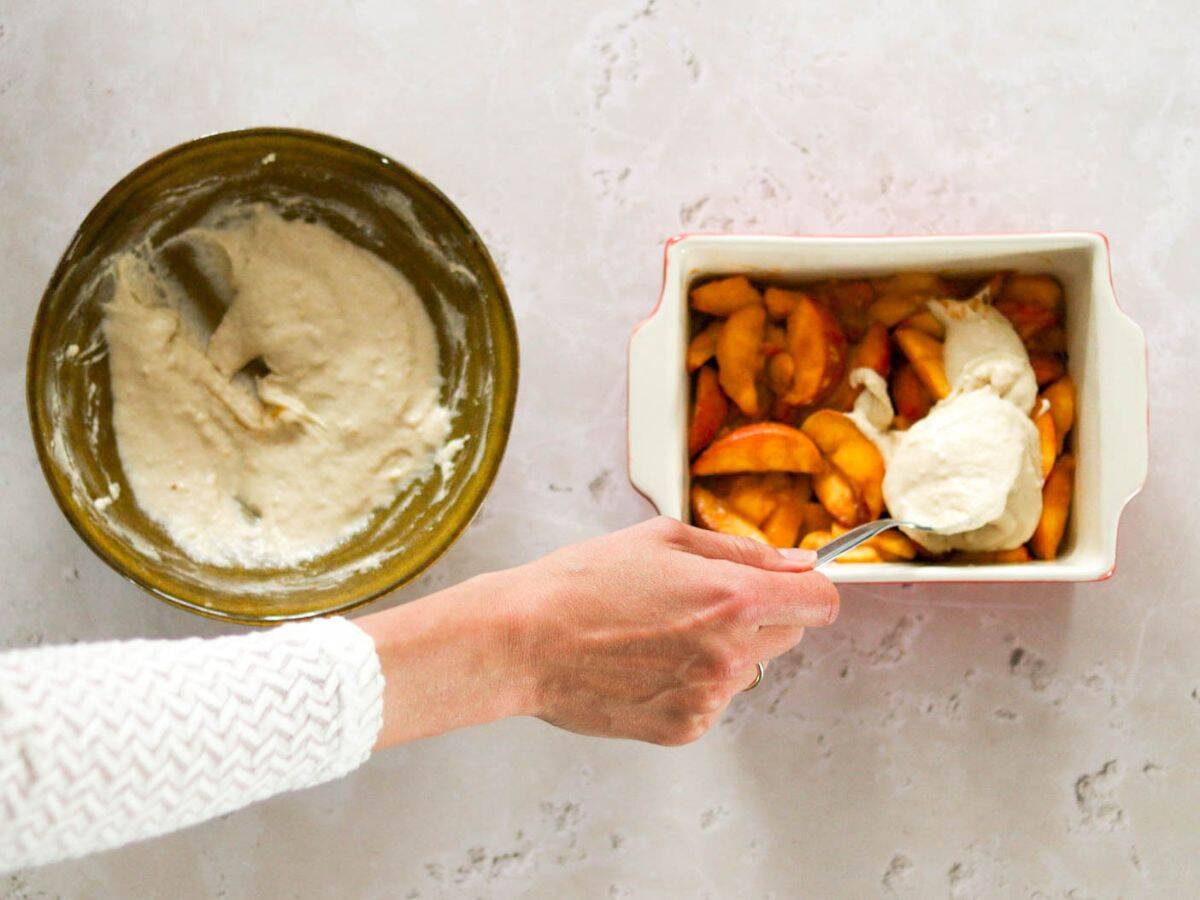 Scooping the batter on top of the sourdough peach cobbler.