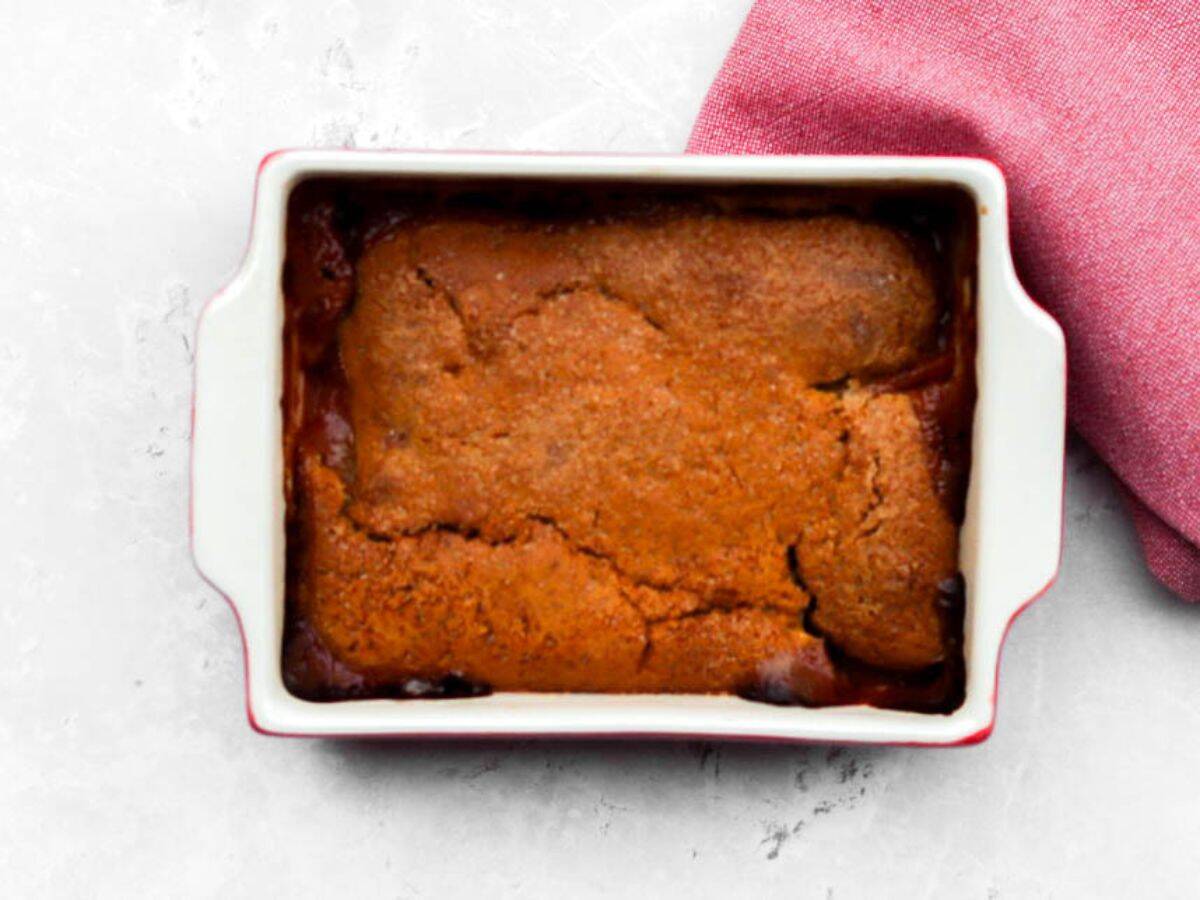 Baked sourdough peach cobbler in a white oven dish.