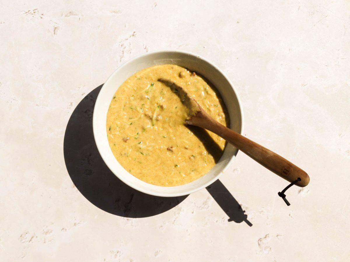 Batter for sourdough zucchini muffins in a yellow bowl.