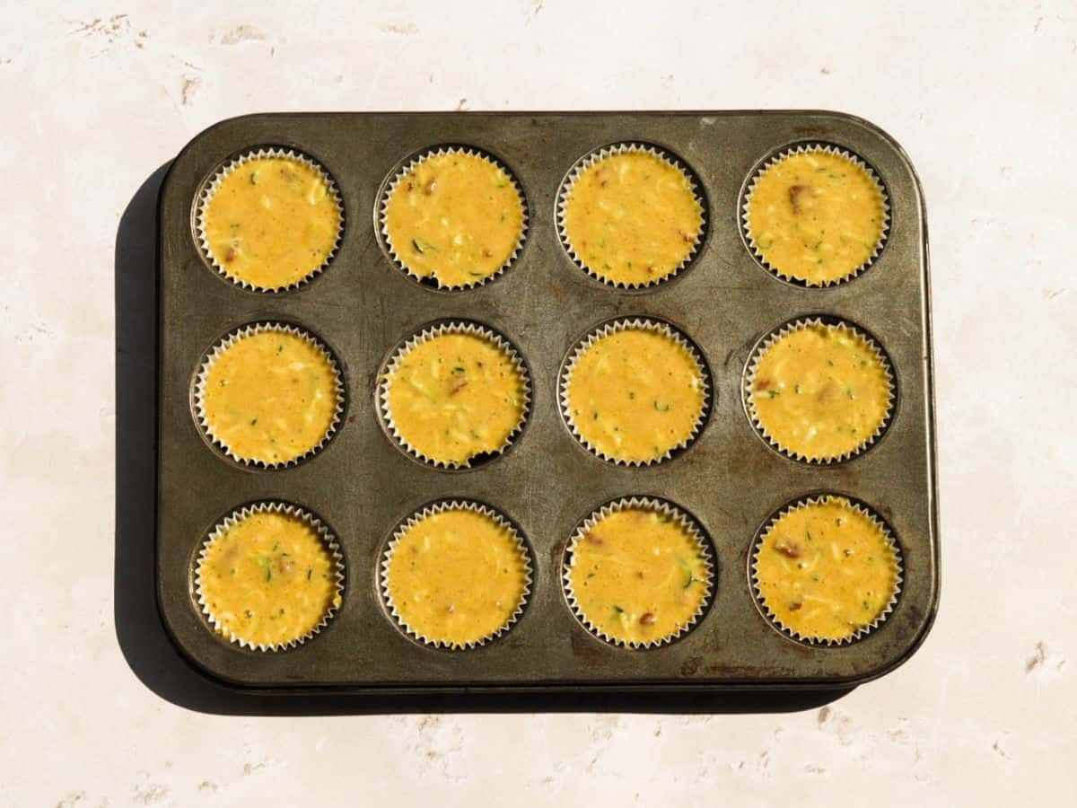 Batter for sourdough zucchini muffins in a muffin tin.