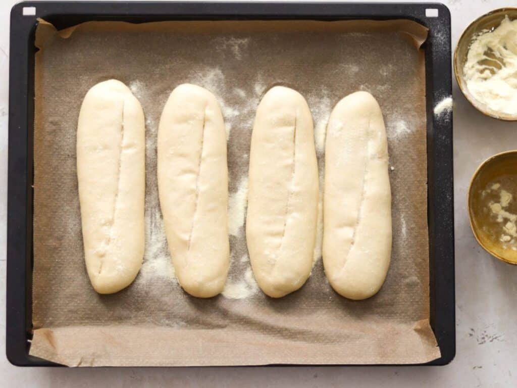 Scoring sourdough sub rolls.