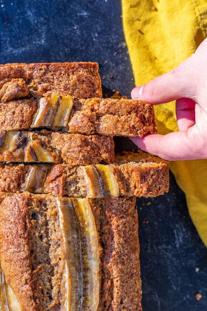 A hand pulling a slice of sourdough banana bread.