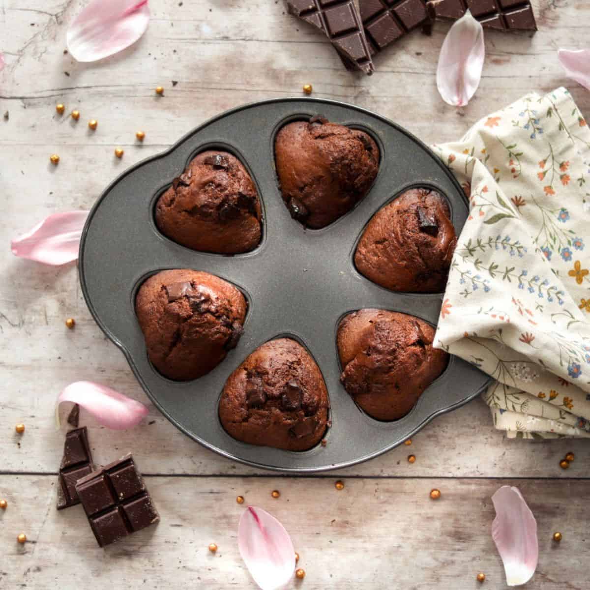 Sourdough chocolate muffins in a muffin tin with a towel.