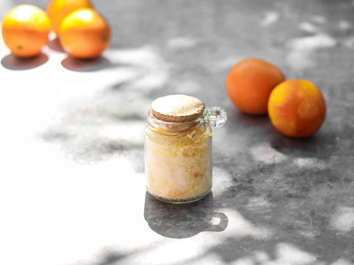 Orange sugar in a jar with fresh oranges.