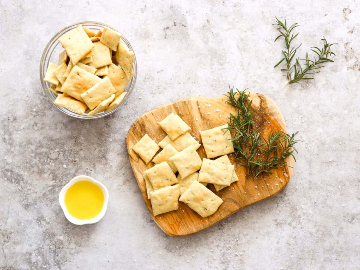 Sourdough discard crackers on a plate with rosemary and olive oil.