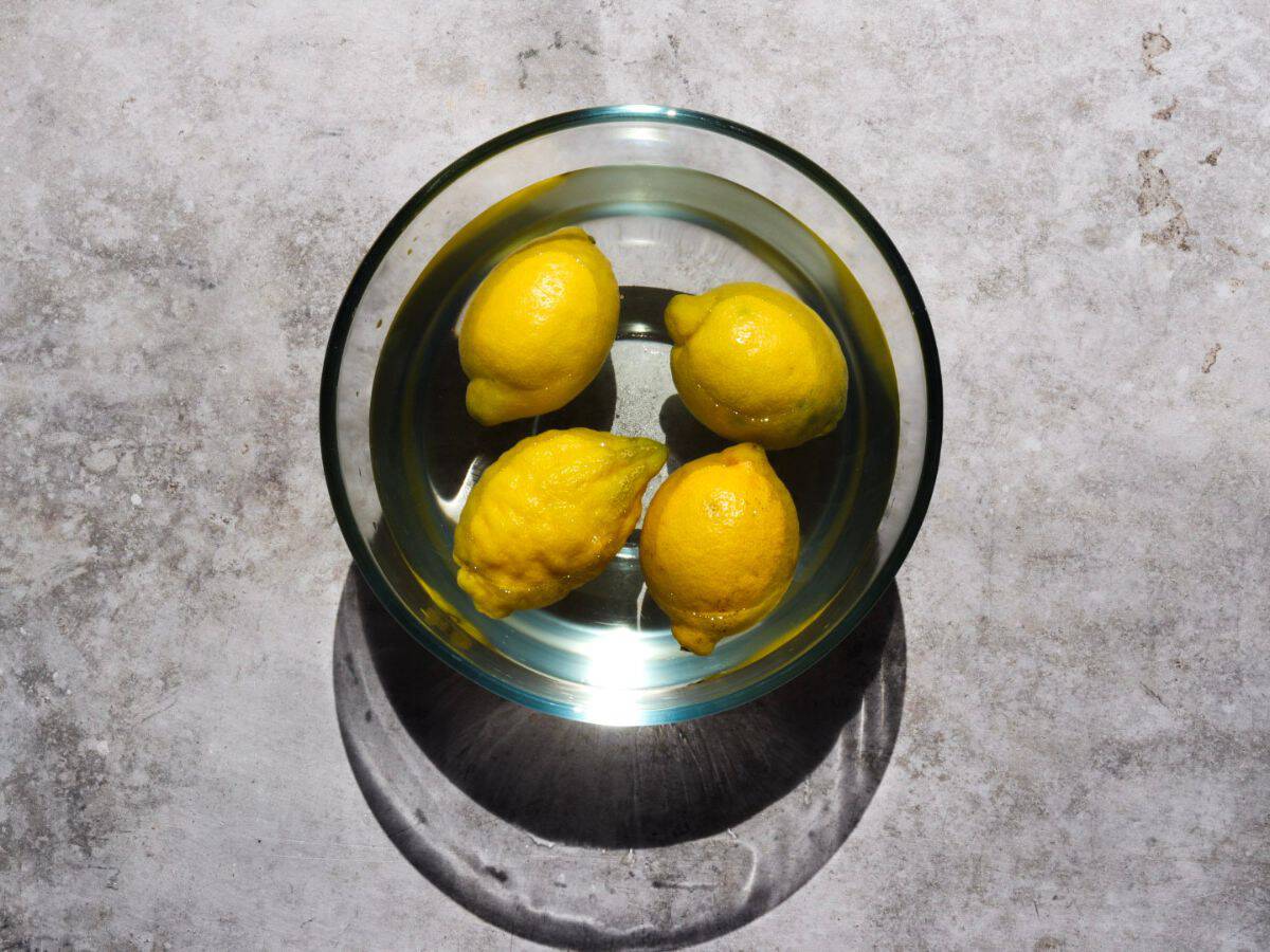 Four lemons in a bowl of water.